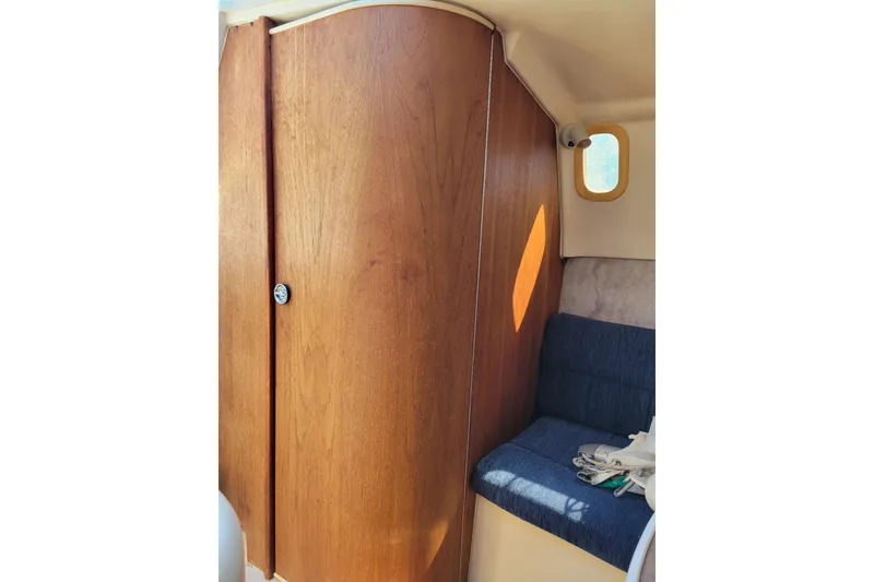 Slide: The Image of Interior of a 2002 Hunter 260 sailboat, featuring wooden cabinetry and a blue cushioned seat. - 3