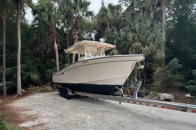 The Image of 2007 Grady-White Bimini 306 boat on trailer, surrounded by lush palm trees. - 1