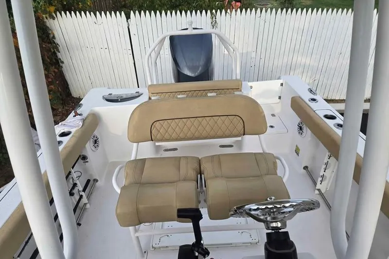 Slide: The Image of 2023 Sportsman Open 232 Center Console boat interior with beige seating and steering wheel. - 2