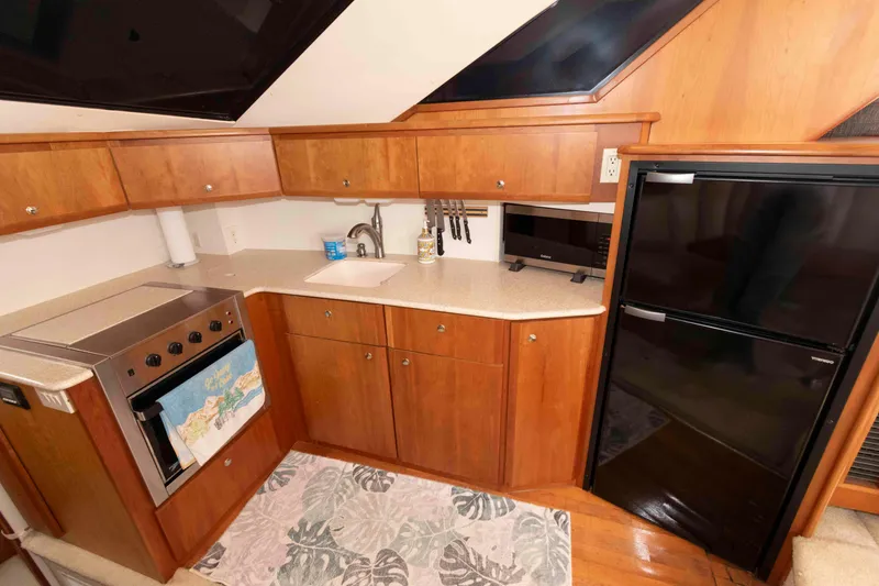 Slide: The Image of 2001 Silverton 392 Motor Yacht kitchen with wood cabinets, stove, sink, and refrigerator. - 15