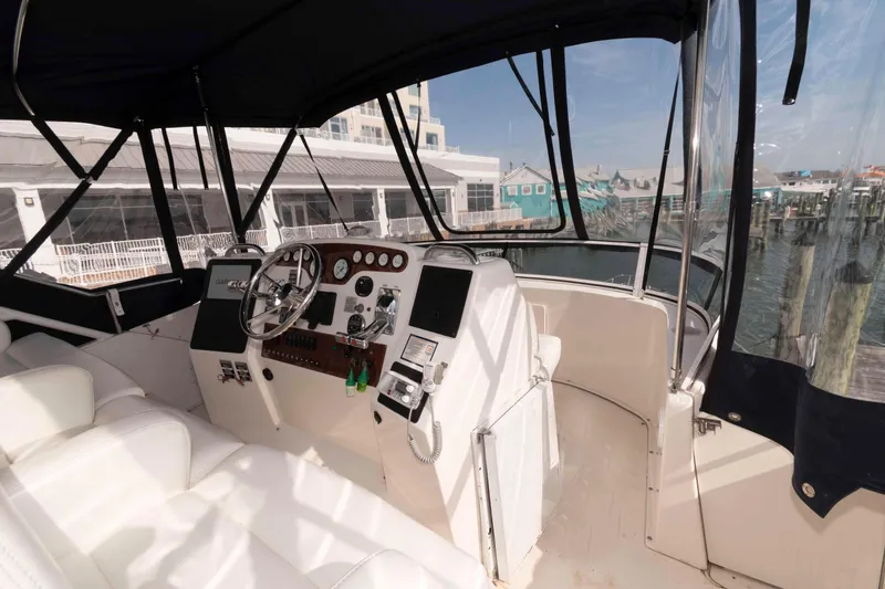 Slide: The Image of 2001 Silverton 392 Motor Yacht helm with steering wheel, gauges, and marina view. - 6