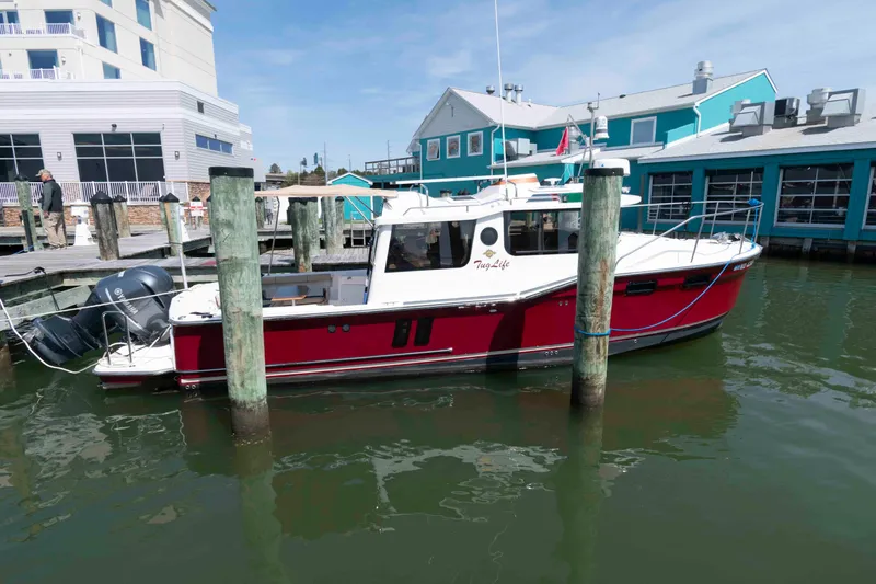 The Image of 2020 Ranger Tugs R-27 docked at marina, vibrant red hull, calm waters. - 0