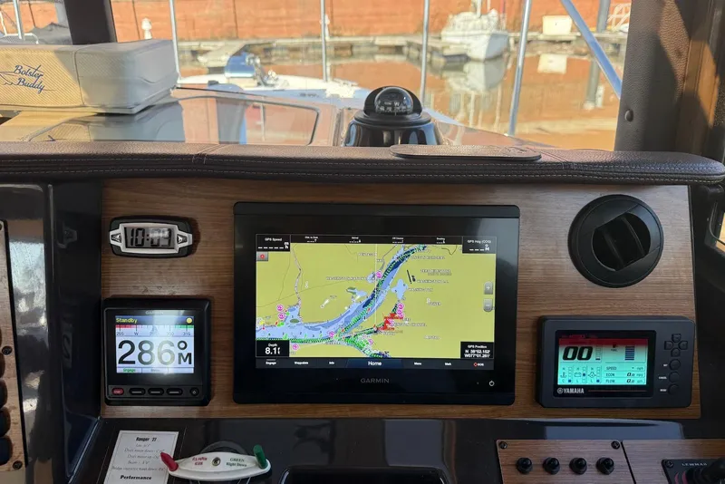 Slide: The Image of 2020 Ranger Tugs R-27 dashboard with navigation and control displays in a marina setting. - 11