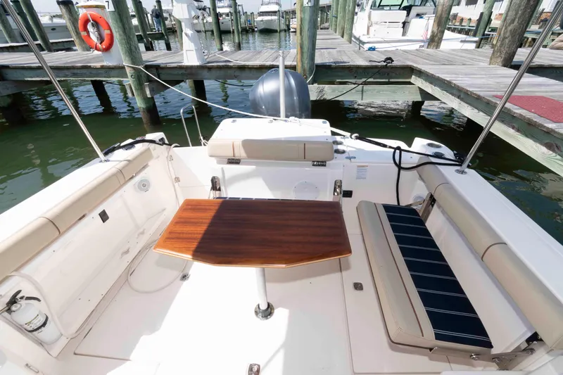 Slide: The Image of 2020 Ranger Tugs R-27 boat cockpit with wooden table and seating at marina. - 3