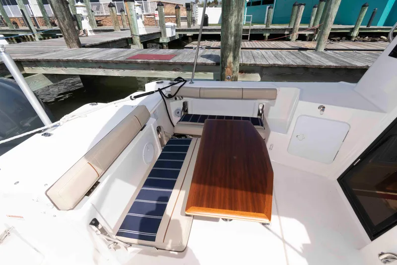 Slide: The Image of 2020 Ranger Tugs R-27 boat interior with seating and wooden table at dock. - 4