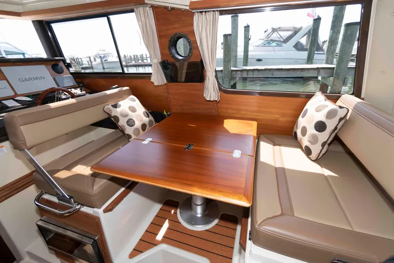Slide: The Image of Interior of 2020 Ranger Tugs R-27 with wood table and cushioned seating. - 6