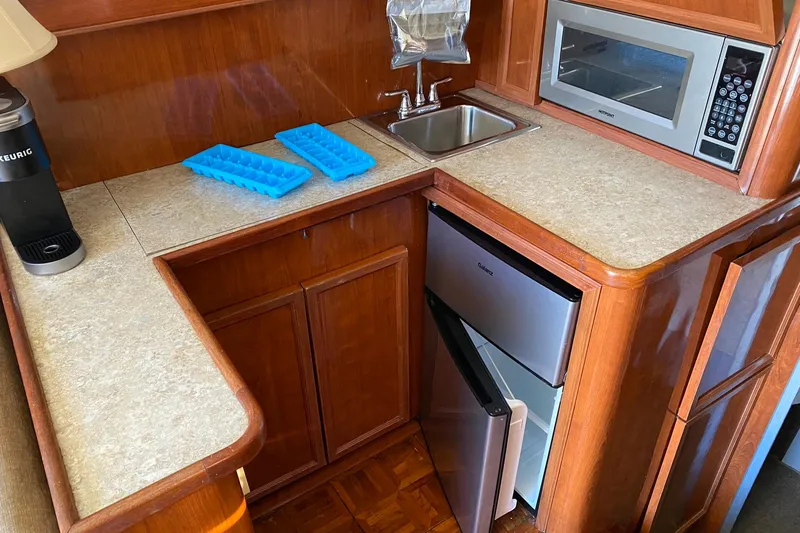 Slide: The Image of 1988 Luhrs Tournament 320 Convertible kitchen with sink, microwave, fridge, and ice trays. - 10