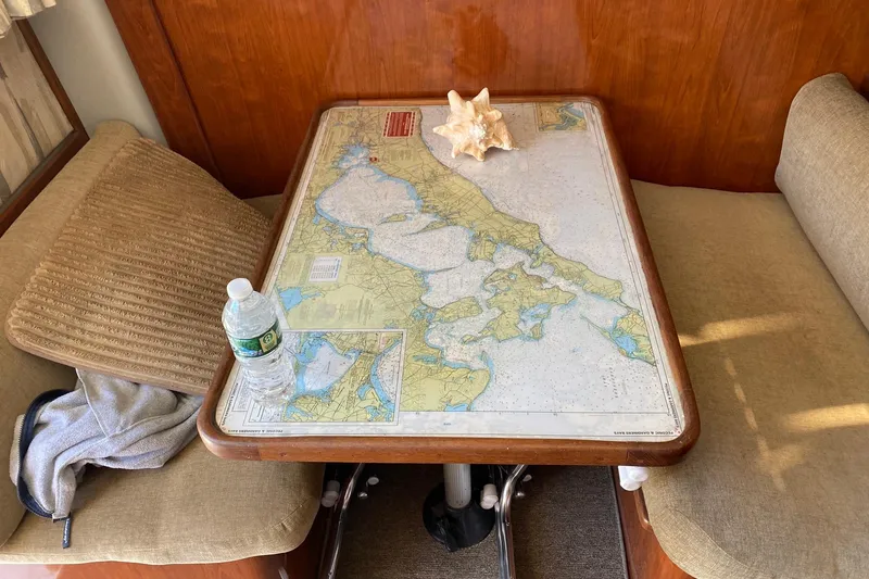 Slide: The Image of 1988 Luhrs Tournament 320 Convertible cabin with nautical chart table and conch shell decor. - 11