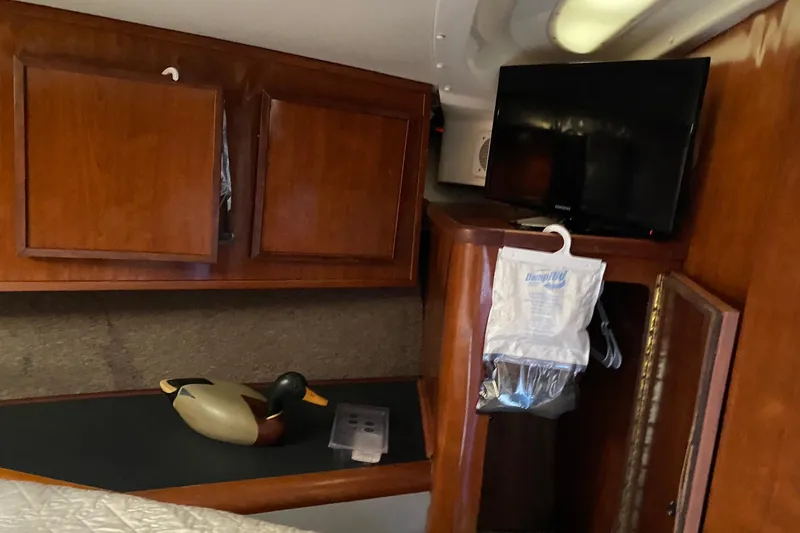 Slide: The Image of 1988 Luhrs Tournament 320 Convertible cabin interior with wooden cabinets and a mounted TV. - 13