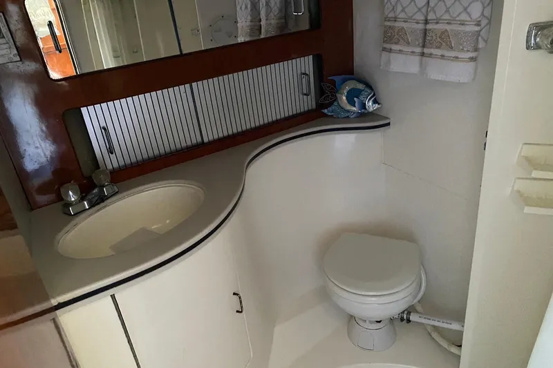 Slide: The Image of 1988 Luhrs Tournament 320 Convertible bathroom with sink, toilet, and decorative fish. - 14