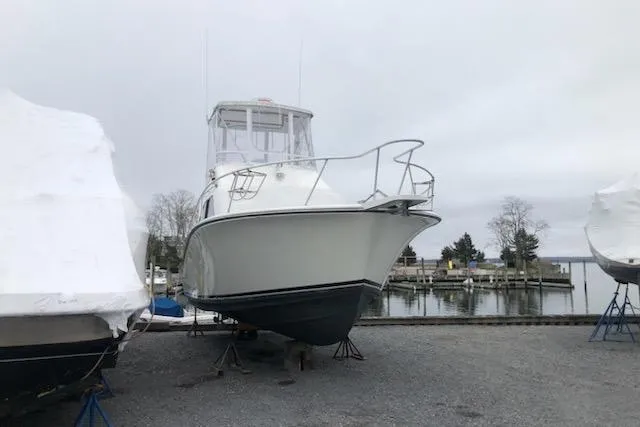 Slide: The Image of 1988 Luhrs Tournament 320 Convertible boat on stands near a marina. - 6
