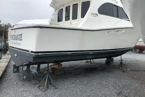 Slide: The Image of 1988 Luhrs Tournament 320 Convertible boat on stands, side view, white hull. - 7