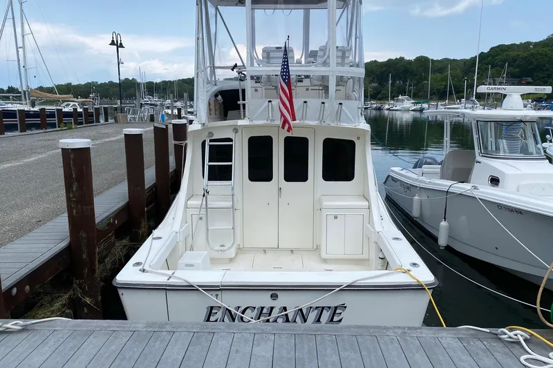 Slide: The Image of 1988 Luhrs Tournament 320 Convertible boat docked, displaying an American flag and "ENCHANTÉ" name. - 8