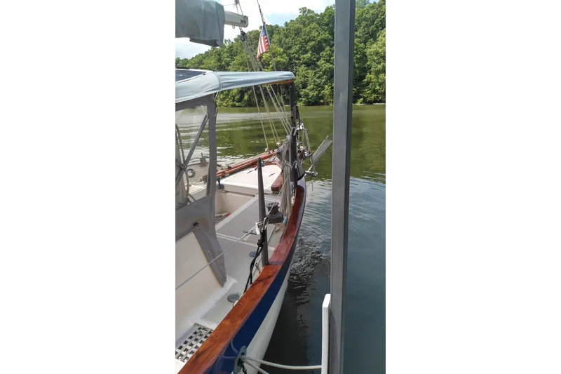 Slide: The Image of 1977 Westsail 32 sailboat docked on a calm river with lush greenery. - 4
