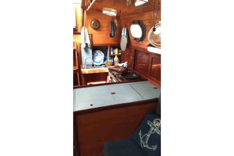 Slide: The Image of 1977 Westsail 32 yacht interior with wooden cabinetry and compact kitchen area. - 5