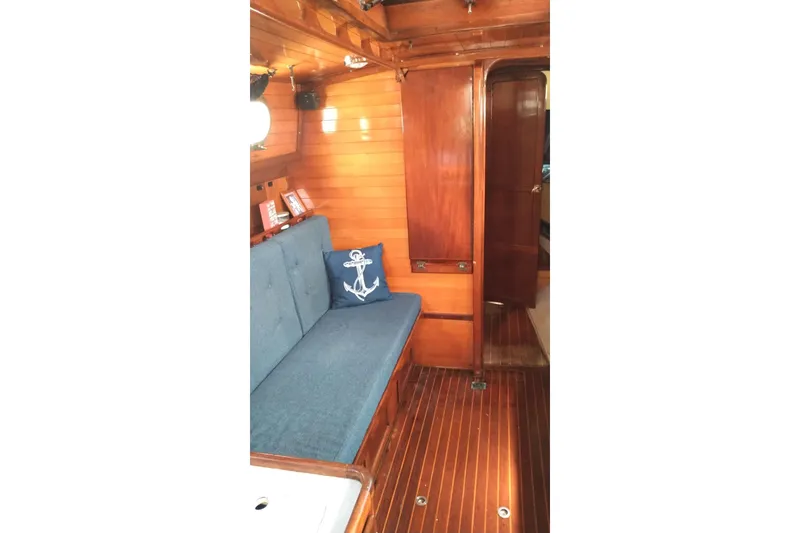 Slide: The Image of Interior of 1977 Westsail 32 sailboat with wooden paneling and blue cushioned seating. - 7
