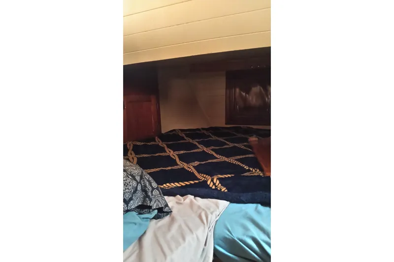 Slide: The Image of Cozy cabin interior of a 1977 Westsail 32 sailboat with nautical-themed bedding. - 8