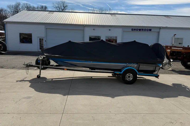 Slide: The Image of 1997 Tuffy 1700 ESOX MAGNUM boat with cover, parked outside a showroom. - 21