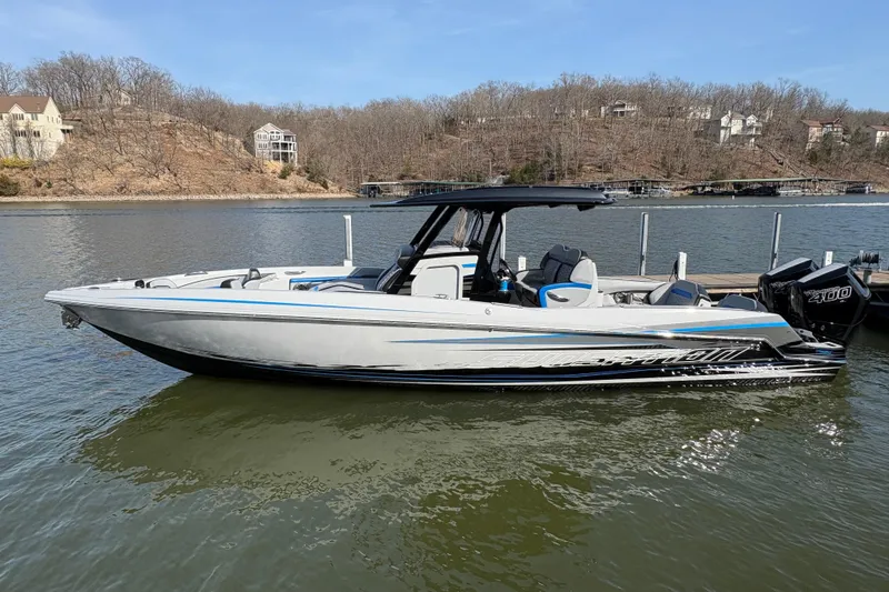 The Image of 2024 Sunsation 32 CCX boat docked on a calm lake, showcasing sleek design and powerful engines. - 0