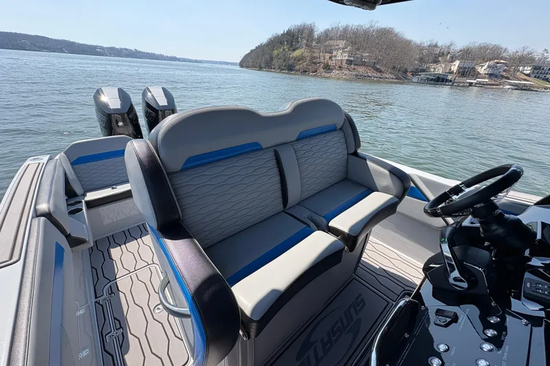 Slide: The Image of 2024 Sunsation 32 CCX boat interior with dual seats and steering, on a scenic lake. - 6