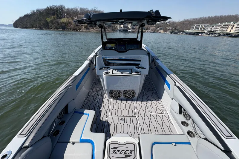 Slide: The Image of 2024 Sunsation 32 CCX boat interior with sleek seating and modern dashboard on a calm lake. - 7