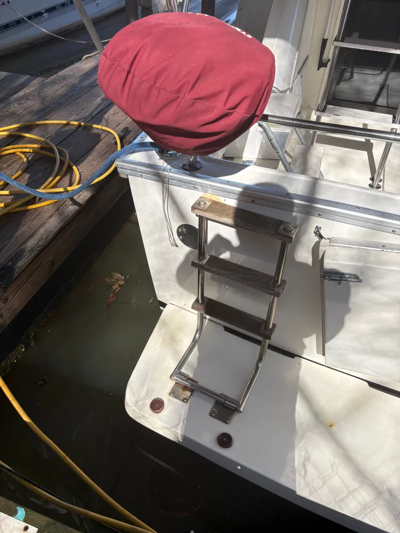 Slide: The Image of 1983 Mainship 34 Mark III with ladder and red cover at dock. - 10