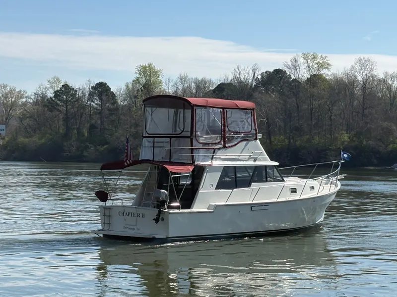 Slide: The Image of 1983 Mainship 34 Mark III cruising on a calm river. - 2
