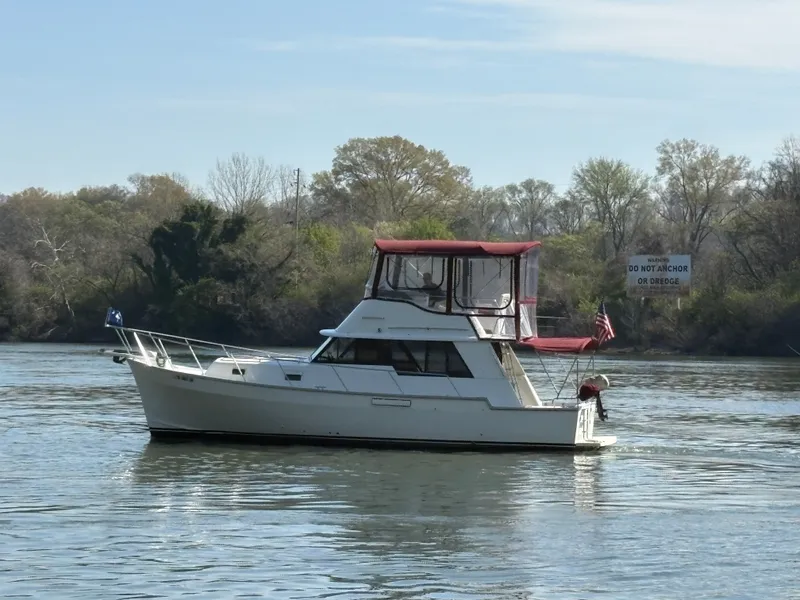 Slide: The Image of 1983 Mainship 34 Mark III anchored on a calm river. - 8