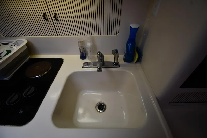 Slide: The Image of 1994 Sea Ray 400 Express Cruiser kitchen sink with faucet and cleaning supplies. - 37