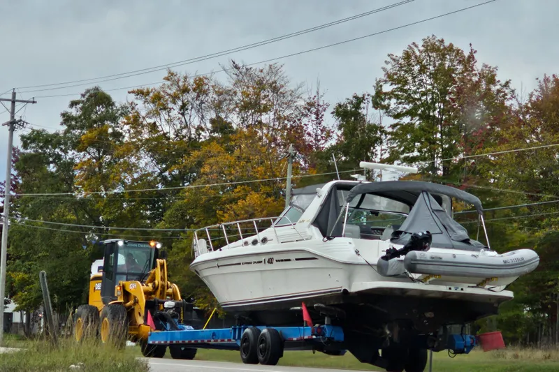 Slide: The Image of 1994 Sea Ray 400 Express Cruiser on trailer, towed by a John Deere vehicle, amidst autumn trees. - 5