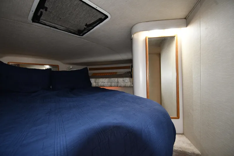 Slide: The Image of Cozy cabin interior of 1994 Sea Ray 400 Express Cruiser with blue bedding and mirror. - 26