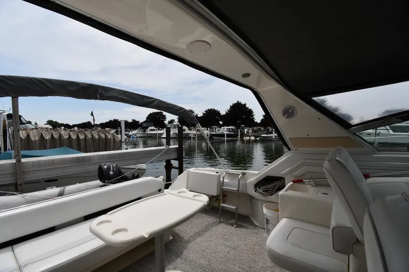 Slide: The Image of 1994 Sea Ray 400 Express Cruiser interior view at marina, featuring seating and table. - 18