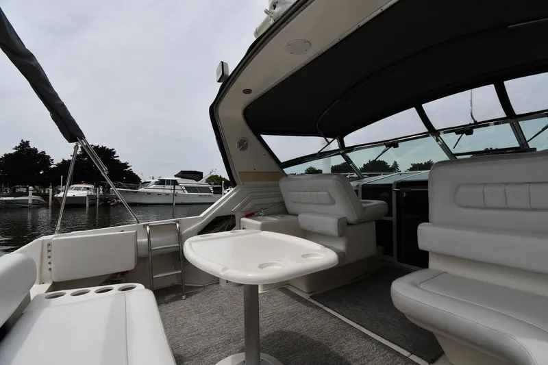 Slide: The Image of 1994 Sea Ray 400 Express Cruiser interior with white seating and table, docked at marina. - 17