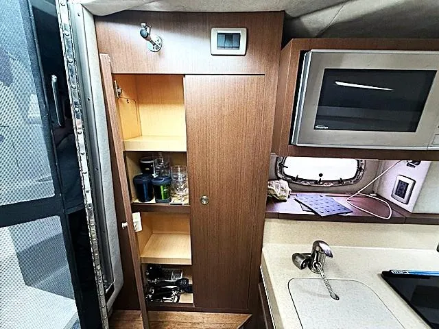 Slide: The Image of 2013 Sea Ray 260 Sundancer interior with kitchenette, microwave, and storage cabinets. - 15