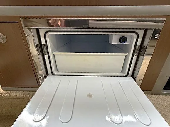 Slide: The Image of 2013 Sea Ray 260 Sundancer interior freezer compartment, open with visible storage bin. - 17