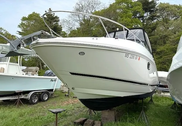 Slide: The Image of 2013 Sea Ray 260 Sundancer boat on land, surrounded by trees and other boats. - 2