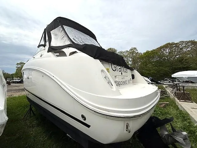 Slide: The Image of 2013 Sea Ray 260 Sundancer boat on land, covered, with trees in the background. - 3