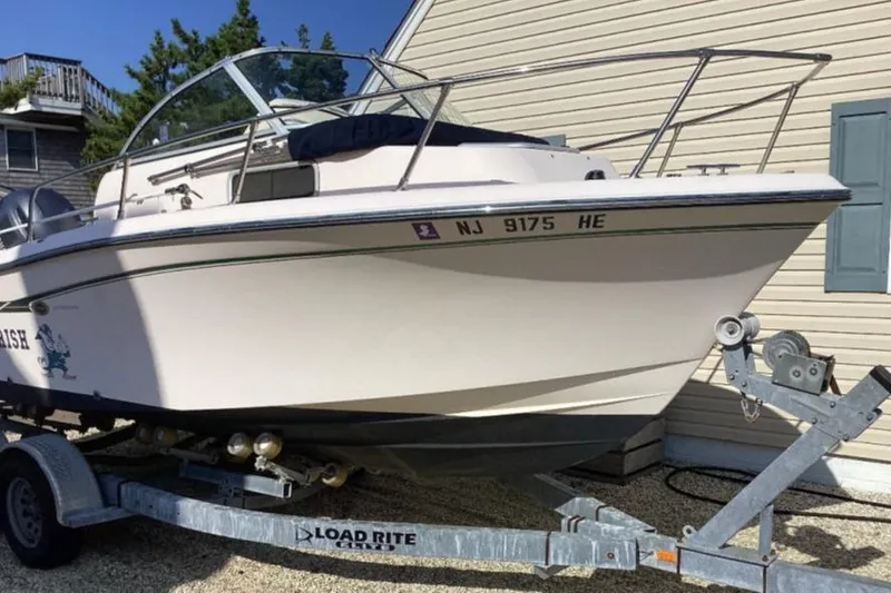 Slide: The Image of 2013 Grady-White Adventure 208 boat on trailer, parked beside a house. - 3