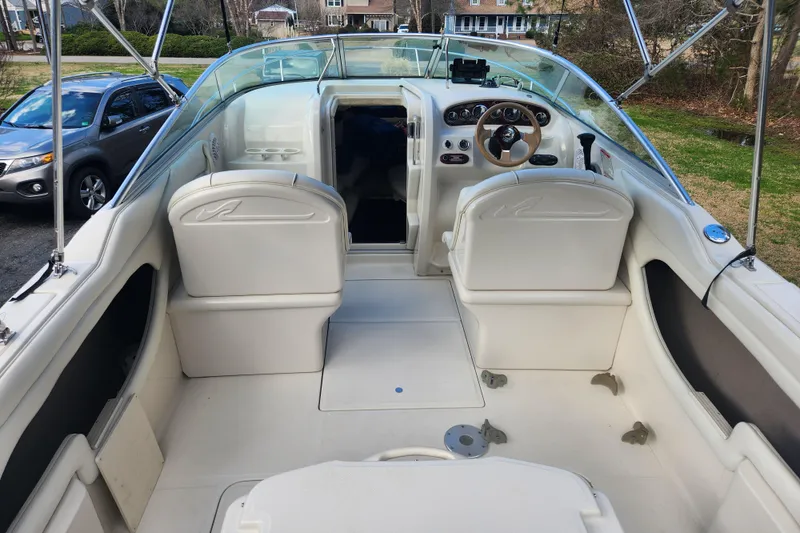 Slide: The Image of 2003 Sea Ray 225 Weekender boat interior with white seating and steering wheel. - 14
