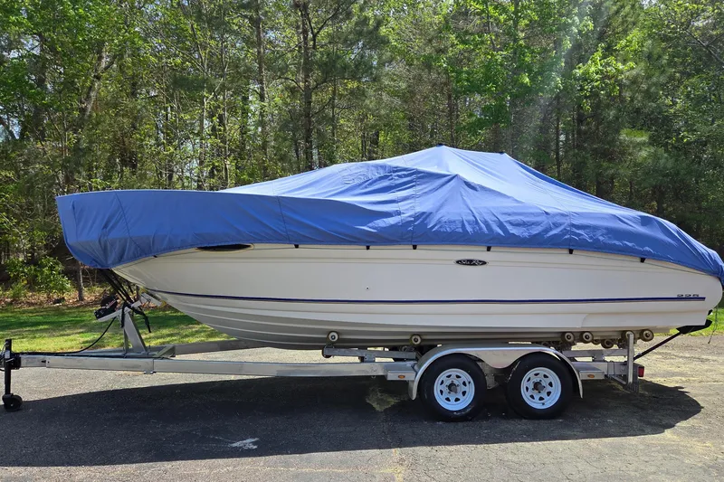 Slide: The Image of 2003 Sea Ray 225 Weekender boat covered with blue tarp on trailer in wooded area. - 23
