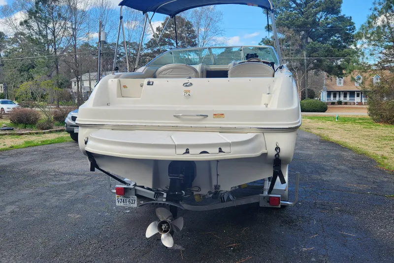 Slide: The Image of 2003 Sea Ray 225 Weekender boat on trailer, parked in a residential driveway. - 3
