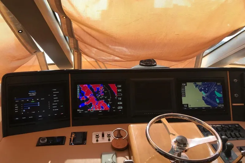 Slide: The Image of 2007 Hatteras yacht helm with navigation screens and steering wheel under a canopy. - 14