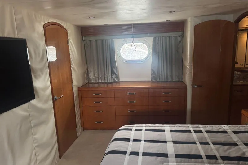 Slide: The Image of Luxurious 2007 Hatteras yacht interior with wood cabinetry, porthole window, and striped bedding. - 21