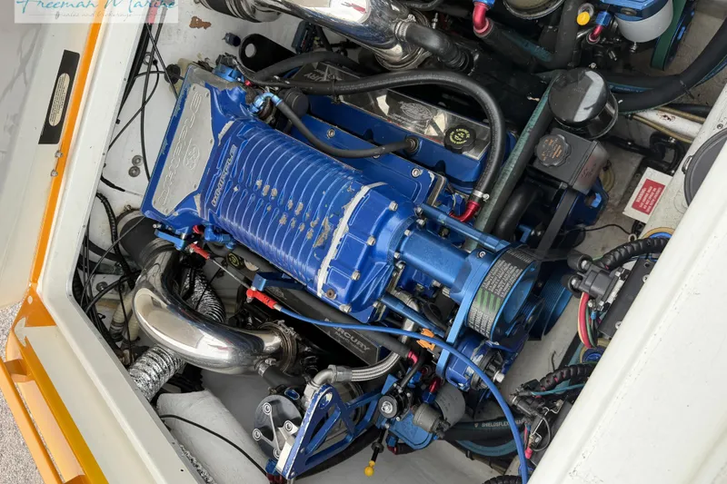 Slide: The Image of Engine compartment of a 2000 Cigarette 30' Mystique boat, featuring a blue supercharger. - 23