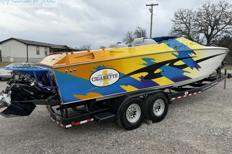 Slide: The Image of 2000 Cigarette 30' Mystique boat with vibrant yellow and blue design on trailer. - 3