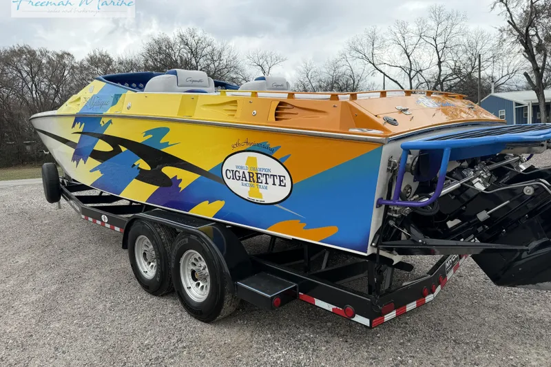 Slide: The Image of 2000 Cigarette 30' Mystique boat with vibrant graphics on a trailer. - 8