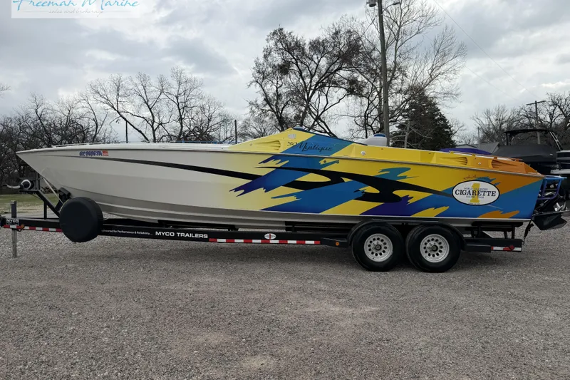 Slide: The Image of 2000 Cigarette 30' Mystique speedboat on trailer, vibrant yellow and blue design. - 9
