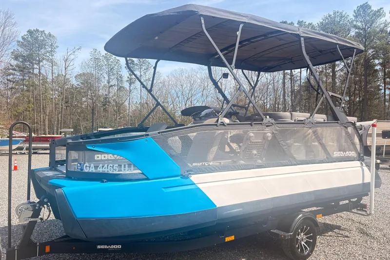 The Image of 2022 Sea Doo Switch pontoon boat with canopy on a trailer in a wooded area. - 1