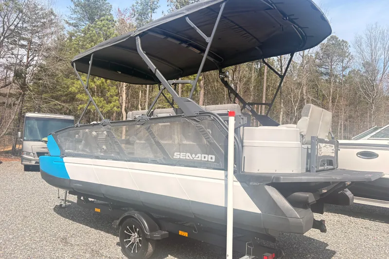 Slide: The Image of 2022 Sea Doo Switch pontoon boat with canopy, parked on gravel. - 2