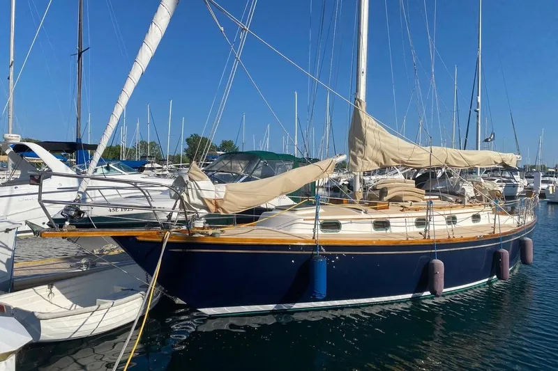 The Image of 1987 Cape Dory 36 sailboat docked in a marina under clear blue skies. - 1